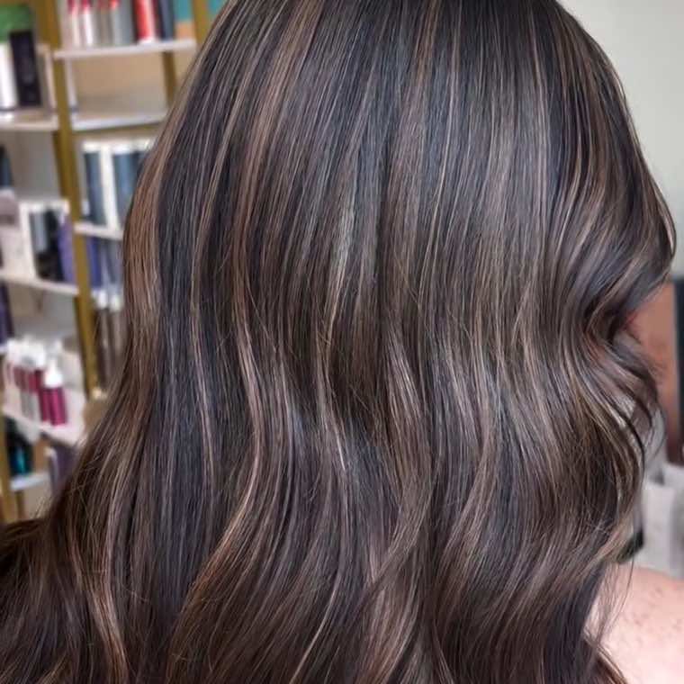Dark brunette waves with fine ribbons of caramel balayage